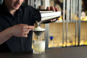 bartender prepares a cocktail in a bar, club. pours alcohol and syrups. uses ice and breaks ice