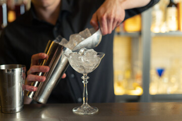 bartender prepares a cocktail in a bar, club. pours alcohol and syrups. uses ice and breaks ice