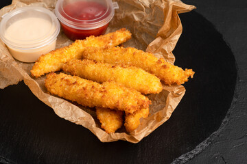 Grilled cheese, cheese sticks on a black background, side view