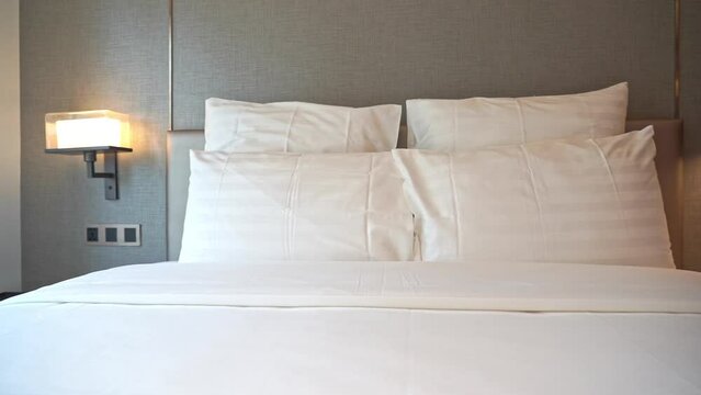 Modern king-size made-up bed with 4 pillows and night lamps attached to the wall