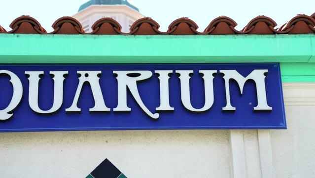 This panning video shows a colorful "aquarium" sign in the sun.