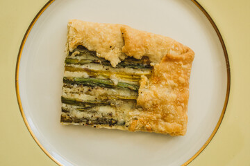 single serving, rectangular slice of an asparagus gruyere galette on golden yellow plate