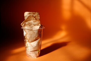 Plastic drinking glass full with used tea bags. Copy space. Close up