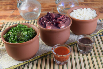 Feijoada typical Brazilian food, beans with pork bacon, orange rice and flour, chili sauce and crackling