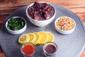 Feijoada typical Brazilian food, beans with pork bacon, orange rice and flour, chili sauce and crackling