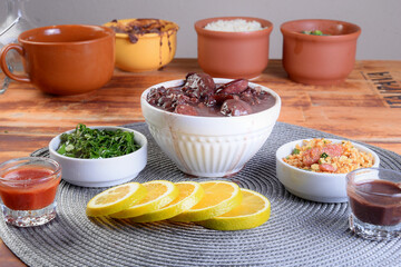 Feijoada typical Brazilian food, beans with pork bacon, orange rice and flour, chili sauce and...