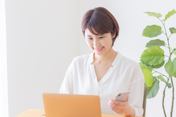 パソコンとスマホを使用する女性