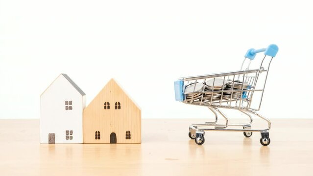 Stop motion animation house and money coin in shopping cart on wooden desk, Property investment and house mortgage financial concept.