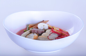 Pink seafood flat noodles (Tom Yum Yen-Ta-Four) with fish ball, dumpling fish, egg and special homemade red sauce serve on white bowl for Thai food  and isolate background with clipping path