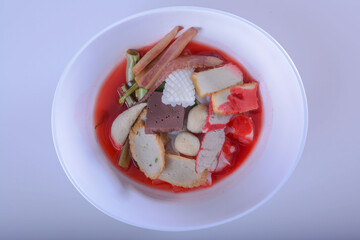 Pink seafood flat noodles (Tom Yum Yen-Ta-Four) with fish ball, dumpling fish, egg and special homemade red sauce serve on white bowl for Thai food  and isolate background with clipping path