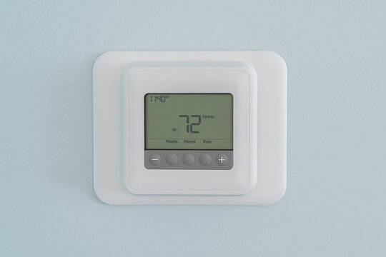 Photograph Of A Modern Residential Programmable Heating And Cooling Thermostat Set At 72 Degrees Mounted On A Blue Wall