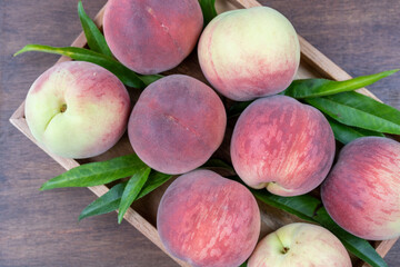 Fresh Sweet Peach on wooden background, Pink and yellow Peach fruit with leaf on wooden plate.
