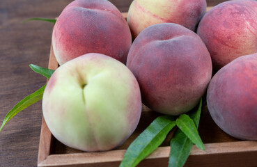 Fresh Sweet Peach on wooden background, Pink and yellow Peach fruit with leaf on wooden plate.