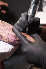 Joven artista de tatuajes barbudos realiza un tatuaje en el brazo de un cliente