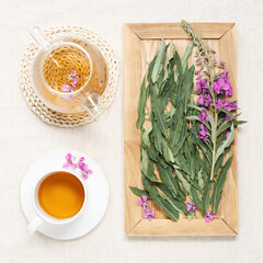 Fireweed tea in white cups and transparent glass teapot, herbal hot tea from green leaves of ivan chai on textile tablecloth. Top view healthy drink and wild flowering willow-herb, tea time
