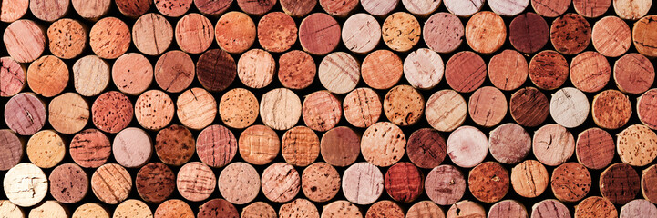 Banner of wine cork from red wine, natural texture used bottle stoppers top view, red gradient. horizontal background from closeup wooden corks. Natural textured stoppers colored wide banner