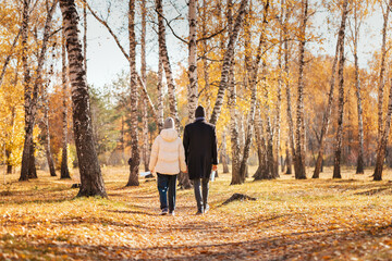 Man and woman, young couple in love holding hands, walking in autumn park, holding disposable medical masks in their hands