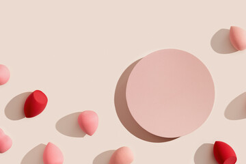 Makeup sponges and geometric pink platform on beige color. Mock up Cosmetic background for product presentation or foundation cream. Top view sponges and podium to show cosmetic products