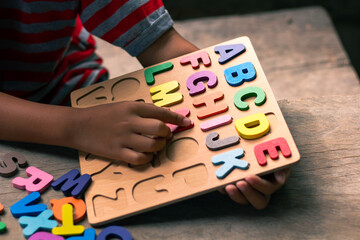 English alphabet made of square wooden. The child's hand grabs the English alphabet to put it in...