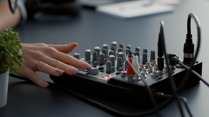 Influencer tweaking audio mixer knobs and buttons. Internet live talk show host changing volumes...