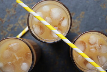 Summer drink iced coffee in tall glass on rustic wooden background. Selective focus, top view