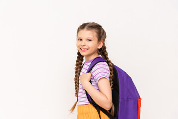 A little girl with a backpack on her back in orange shorts on a white isolated background. Summer educational courses for children.