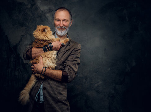 Portrait Of Smiling Old Man Posing Hugging His Purebred Persian Cat With Orange Fur.