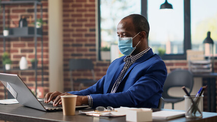 Company employee analyzing business statistics research to plan management project on laptop. Specialist with face mask working on presentation strategy with online paperwork. Tripod shot.