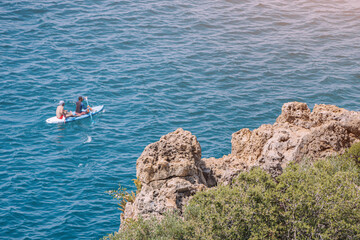 Two people rowing on kayak or sap board swim and travel along the coastal sea zone at the resort