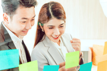 Young businesswoman office worker reading sticky notes on planning glass board, female corporate...
