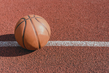 Old orange ball for basketball lying on the rubber sport court.Sport red ground outdoor in the yard.Top view,Copy space.
