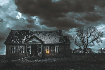 Old wooden house,dramatic clouds at night. Abandoned Haunted Horror House.Near is one tree at night...