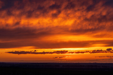 Sun sitting on the horizon against the background of colorful clouds in the sky 