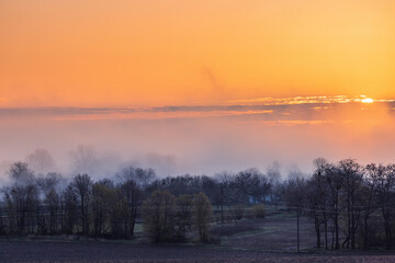 Colorful sunrise over trees, fields and village in spring in Ukraine