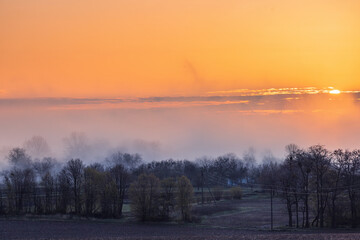 Colorful sunrise over trees, fields and village in spring in Ukraine