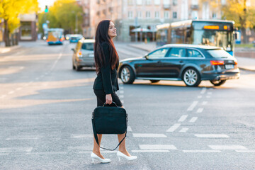 Fototapeta premium Young pretty business woman commuting and walking in city street with laptop bag.Side view,copy space.full-length.