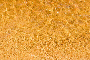 Abstract Transparent and clean yellow water background with sunlight reflection, top view,summer natural day shot.Copy space.