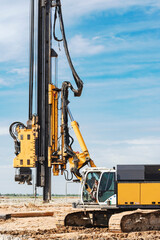 Hydraulic drilling machine at the construction site. Pile field. Modern drilling rig. The device of piles on the background of the blue sky. Work drilling rig when driving bored piles.