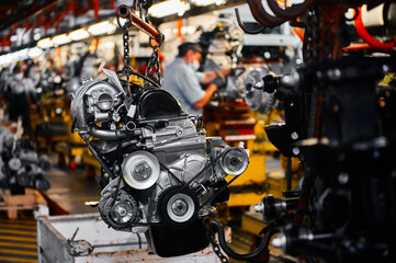 Fototapeta premium Car motor hangs on chains in assembling plant workshop