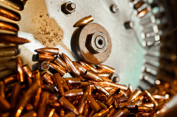 Pile of orange bullets and turning wheel at production line - obrazy, fototapety, plakaty