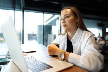 Young businesswoman sitting in a cafe and working with laptop