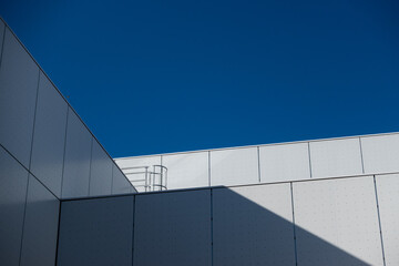 Details of a white modern public building. Subject photographed against a blue sky on a sunny afternoon