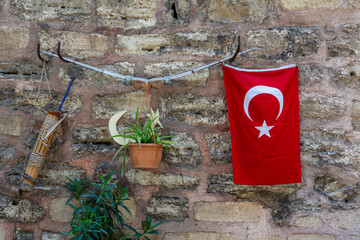 A bow with a quiver and arrows, a Turkish flag and a flower in a pot are hung on a stone wall