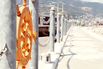 Perspective view of concrete walkway and metal railing decorated with chain and steering wheel...