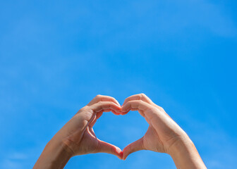 Hands making shape of heart against the sky. Love, friendship concept.