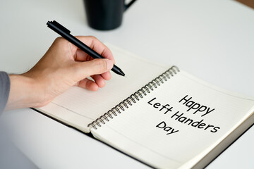 left handed man writes in a notebook on the table, International Left-handers Day
