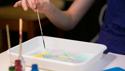 Girl draws with a stick on the water. Image with selective focus