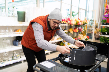 a man in a store chooses a suitable grill for an outdoor picnic