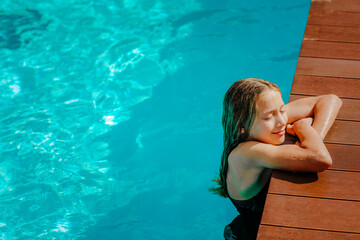 Girl in summer bikini posing in the pool with copy space.