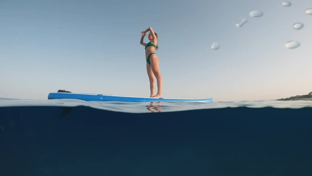 Girl does Yoga on the stand up paddle sup in Summer in the sea